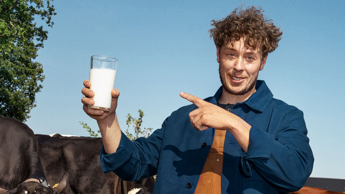 Bonde håller i mjölkglas