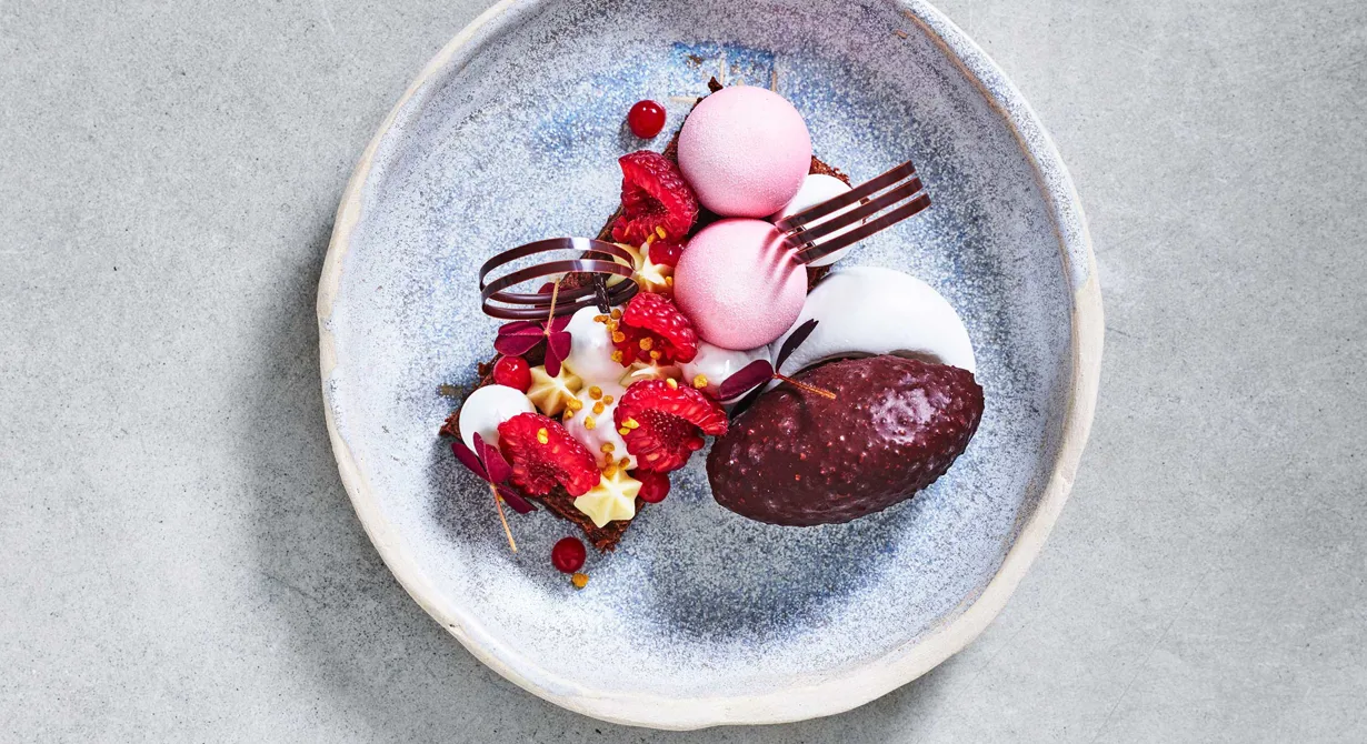 Den här vackra tallriksdesserten består av chokladbrownie som toppas med hallonchantilly, sudachicrémeux och mjuk maräng. Till det serveras dessutom en färskostglass på hallon gömd i ett krispigt chokladhölje.