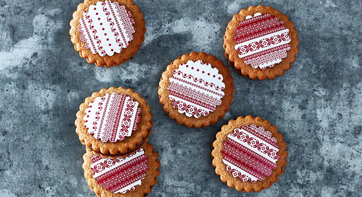 Spritsa en kryddad chokladtryffel mellan två pepparkakor och lägg en julig schablon i choklad på den översta. Fina att säljas i cellofanpåse till advent och jul.