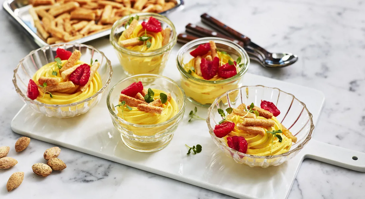 Saffranspannacottan kan lagas i god tid. Vispa pannacottan luftig och lägg på sprits. Spritsa i glas vid servering och garnera med biskvier och hallon. Det här är en dessert som passar på julbordets dessertbord.
