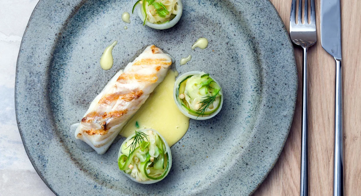 En elegant rätt att erbjuda era gäster. Snabbrimmad, grillad torsk med suröl i smörsåsen istället för vin. Grönsaksstrimlorna sauteras i såsen och läggs som nystan i lökskålarna. Korianderroten bara anas, men ger en härlig smak.