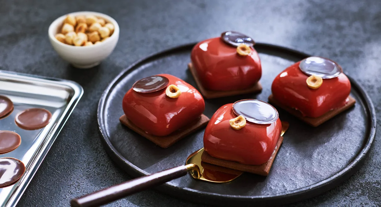 Bakelsen har en interiör av choklad och hasselnöt samt en gräddig färskostmousse som får en lätt syra av crème fraiche. Ställ gärna bakelsen på en platta av mördeg.